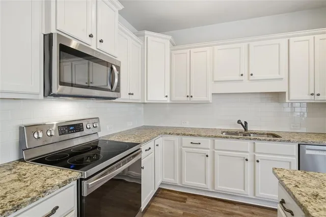 a kitchen with granite countertop a stove sink and microwave