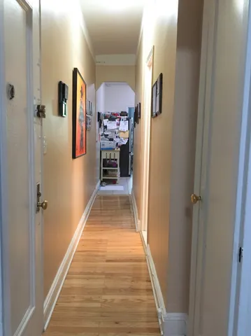 a view of a hallway with front door and wooden floor