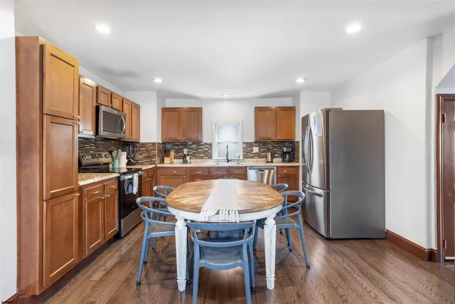 a kitchen with stainless steel appliances granite countertop a refrigerator a stove top oven a sink dishwasher and white cabinets with wooden floor