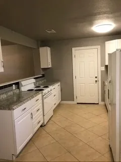a kitchen with granite countertop a sink a refrigerator and cabinets