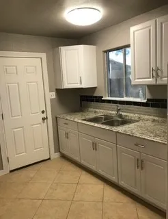 a kitchen with granite countertop a sink window and cabinets