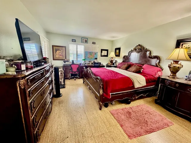 a bedroom with a bed and a dresser with wooden floor