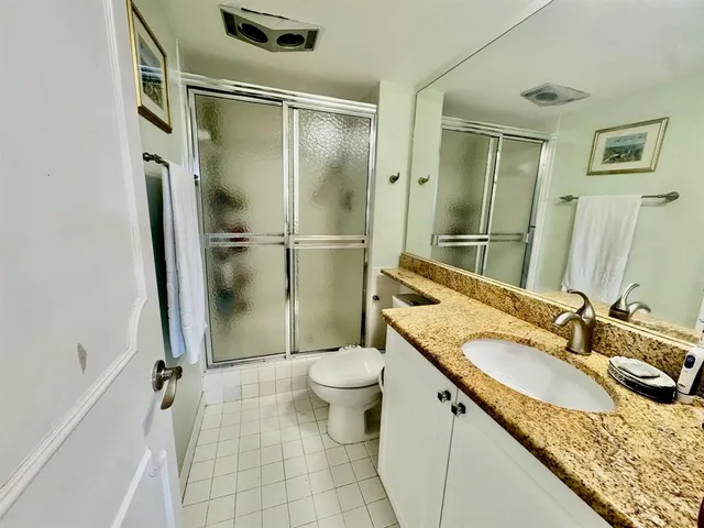 a bathroom with a granite countertop sink toilet and shower