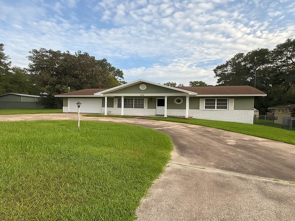 a view of a house with a big yard and large trees