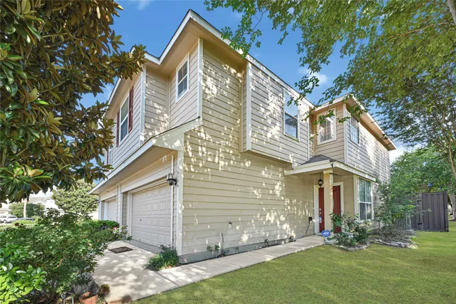 a view of a white house next to a yard with big trees