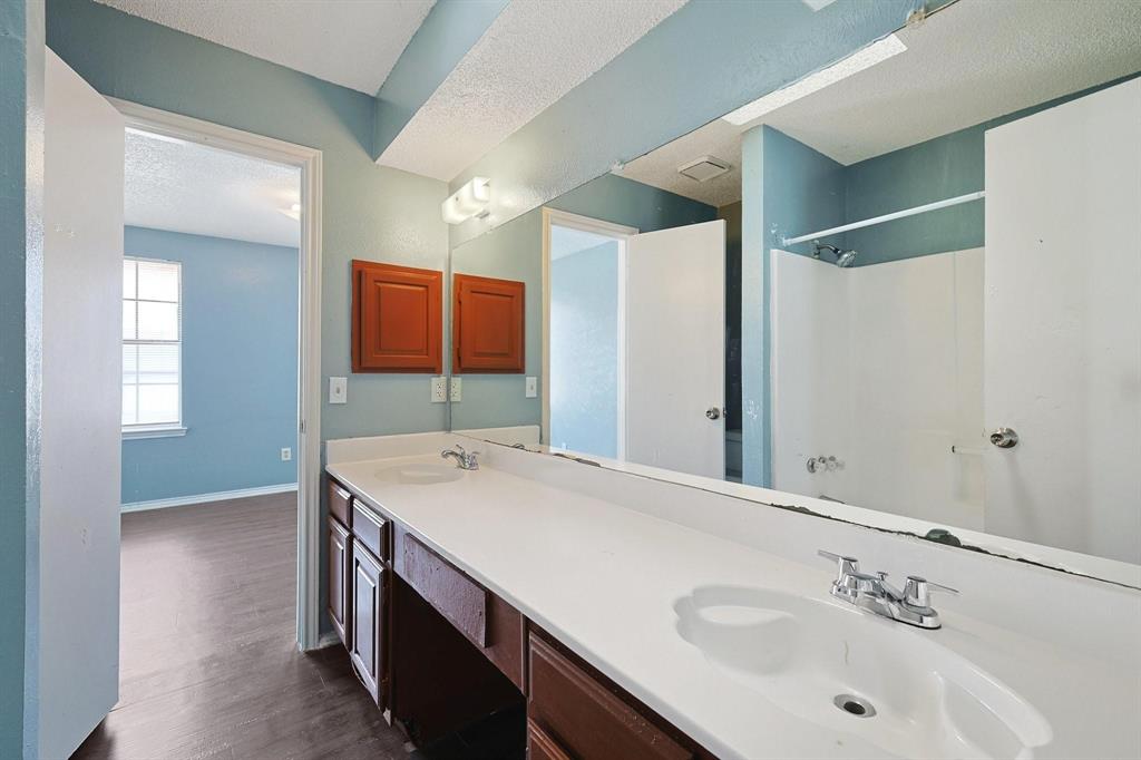 8005 Rothington Road, Unit 1117 Dallas, TX 75227 - Photo 11 of 13 Full bathroom featuring dark wood finished floors, double vanity, a textured ceiling, and a shower