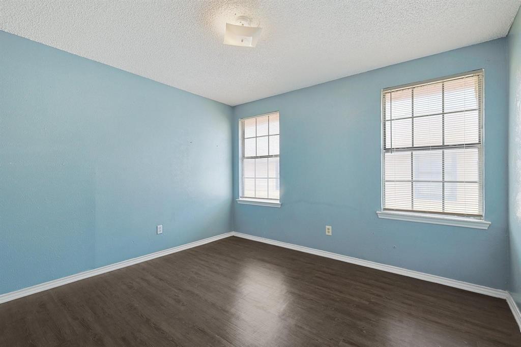 8005 Rothington Road, Unit 1117 Dallas, TX 75227 - Photo 2 of 13 Empty room featuring dark wood-type flooring and a textured ceiling