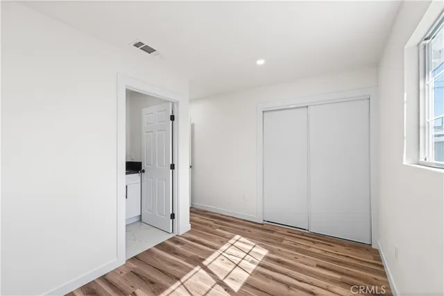 a view of a bedroom with wooden floor and bathroom