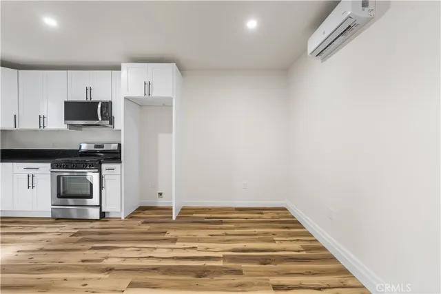 a view of kitchen with stainless steel appliances wooden floor and a sink
