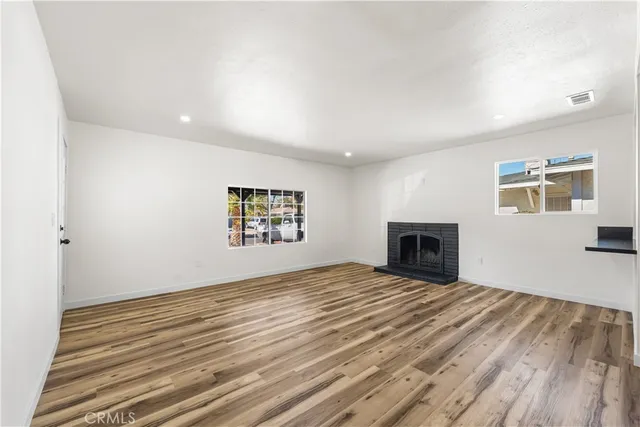 a view of empty room with fireplace and wooden floor