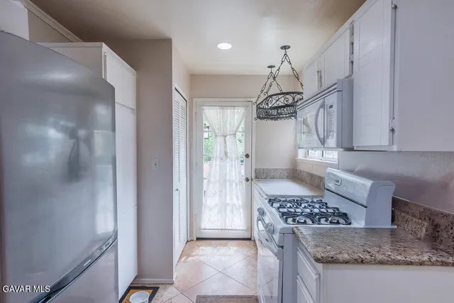 a kitchen view with granite countertop a refrigerator and a stove top oven