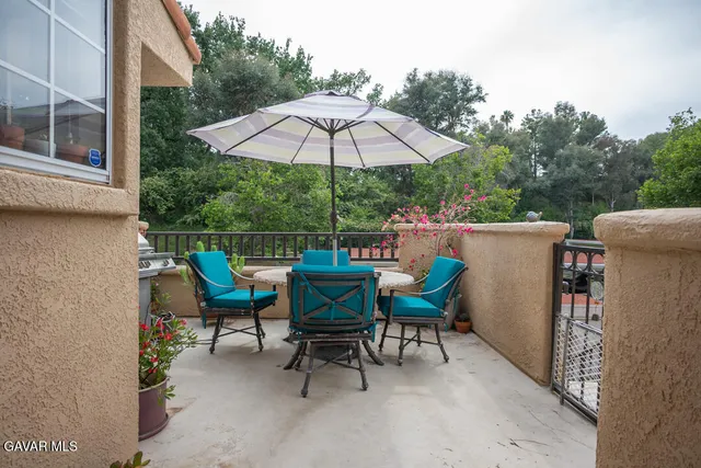 a view of a chairs and table under an umbrella in backyard