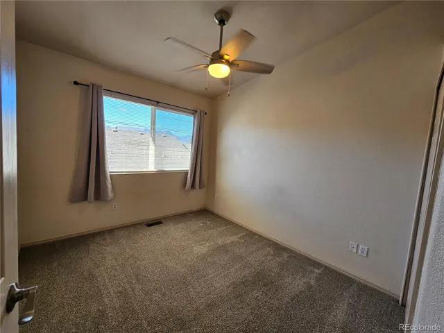 an empty room with a fan & a ceiling fan