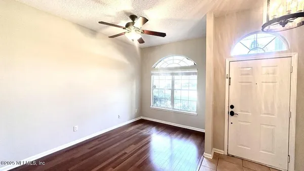 an empty room with wooden floor fan and windows