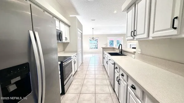 a kitchen with stainless steel appliances granite countertop a refrigerator a sink dishwasher and white cabinets with wooden floor