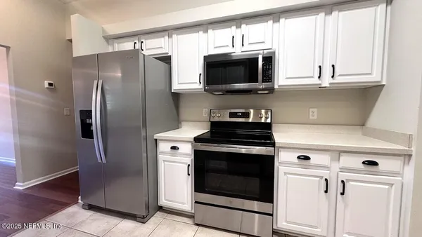 a kitchen with stainless steel appliances white cabinets a stove and a microwave