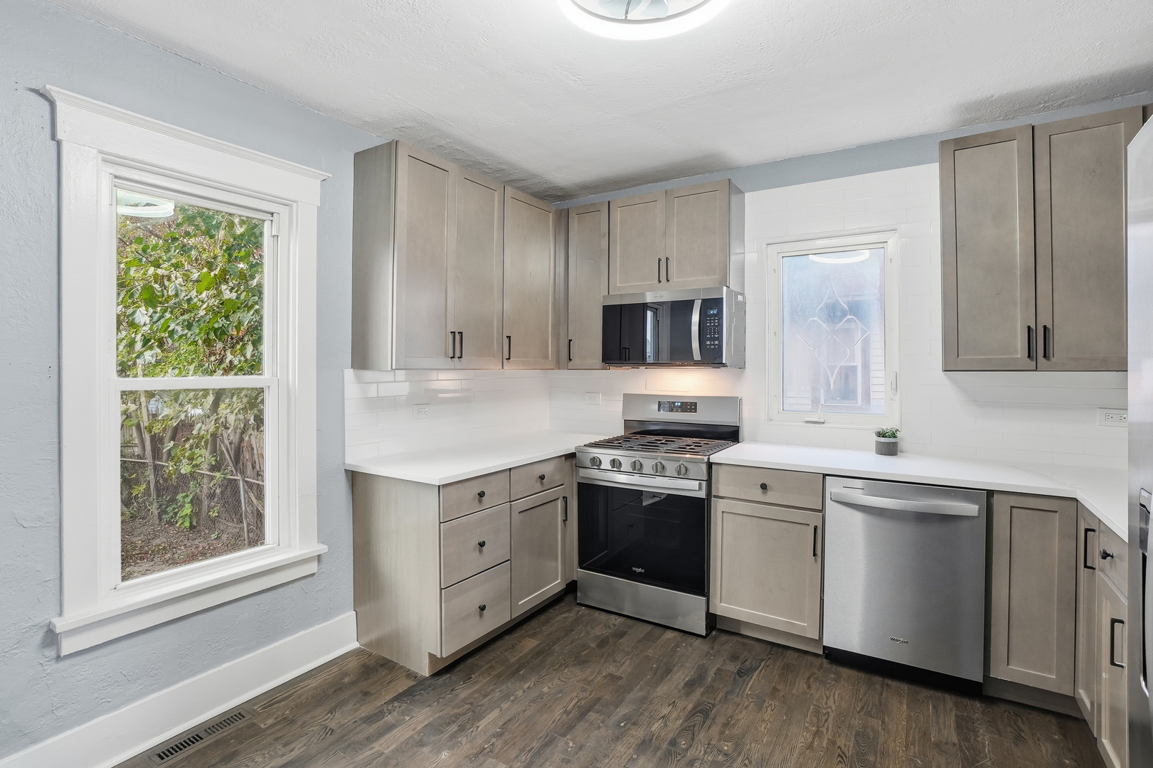 446 South Jackson Street Waukegan, IL 60085 - Photo 3 of 20 a kitchen with stainless steel appliances granite countertop white cabinets a sink dishwasher a stove and a refrigerator with wooden floor