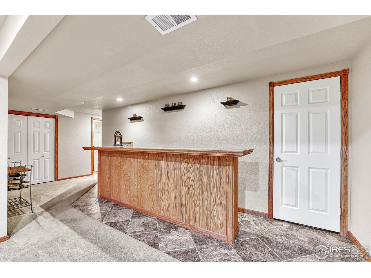 2608 Pleasant Valley Road Fort Collins, CO 80521 - Photo 23 of 40 Built-in bar in basement with bar fridge and small microwave. Unfinished storage area behind door to the right.
