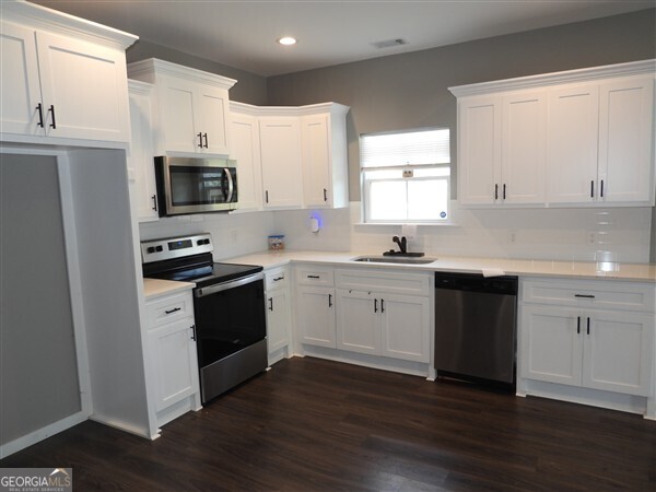 5915 Rye Patch Road Ludowici, GA 31316 - Photo 4 of 25 a kitchen with granite countertop white cabinets and stainless steel appliances