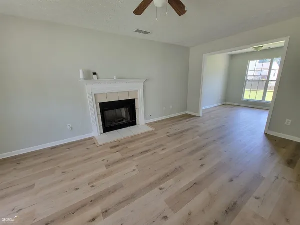 an empty room with wooden floor fireplace and windows