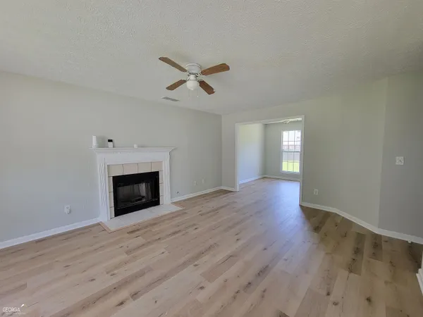 a view of empty room with wooden floor and fireplace
