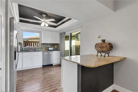 a kitchen with stainless steel appliances granite countertop a sink cabinets and wooden floor