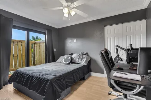 a bedroom with a bed a desk and chair with wooden floor