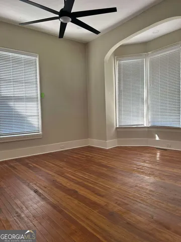 a view of an empty room with wooden floor and a window