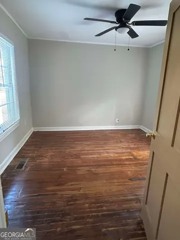 an empty room with wooden floor fan and windows