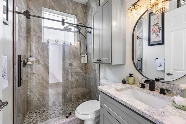 a bathroom with a granite countertop sink toilet and shower