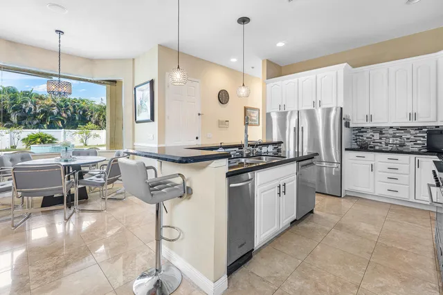 a kitchen with stainless steel appliances kitchen island granite countertop a stove a sink a refrigerator and cabinets