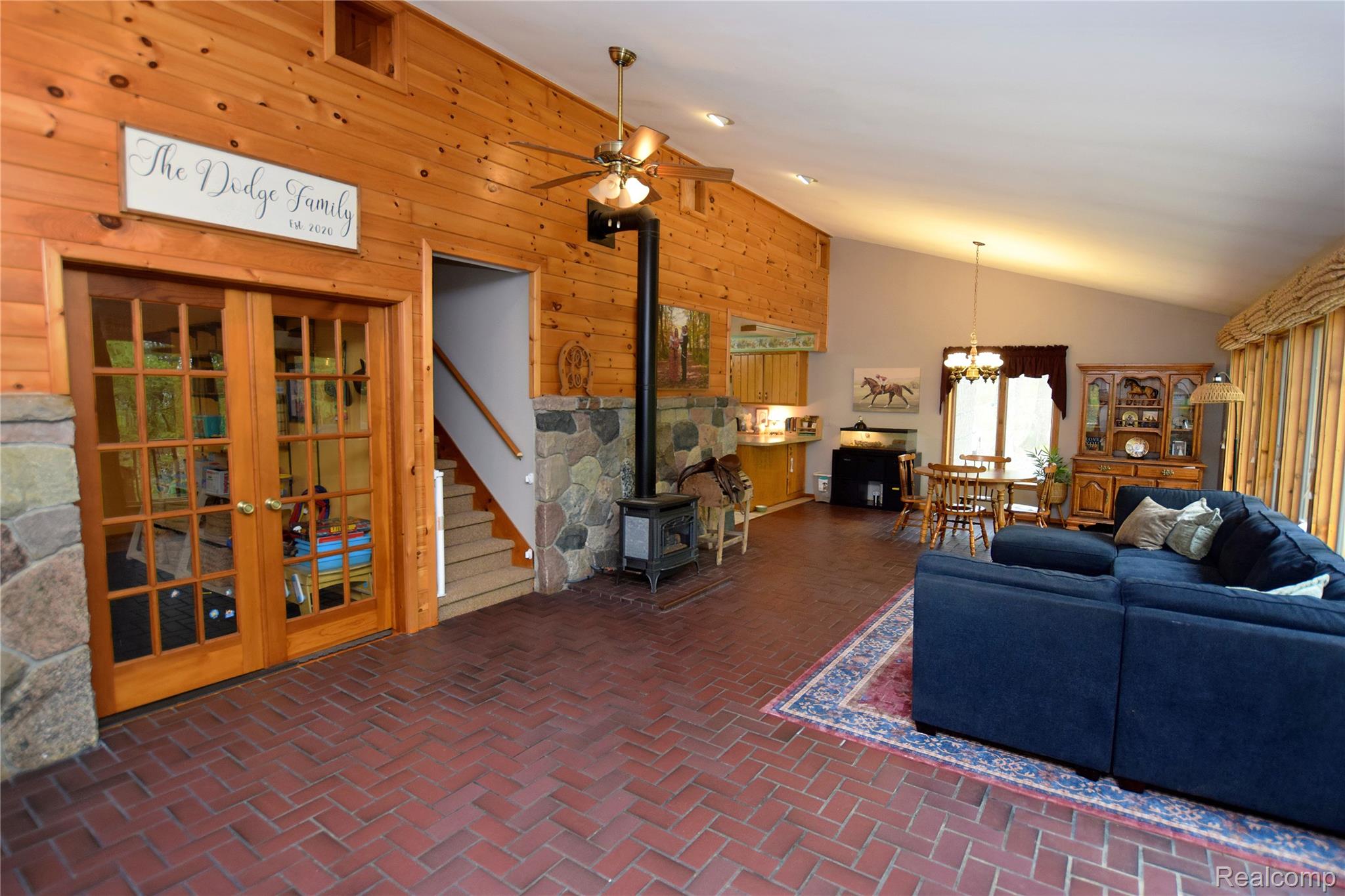 3910 Joy Road Metamora, MI 48455 - Photo 9 of 26 Living area with wooden walls, a wood stove, a ceiling fan, suspended lighting, and vaulted ceiling