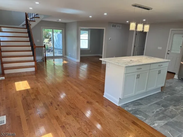 a view of kitchen with stainless steel appliances kitchen island wooden floor and living room