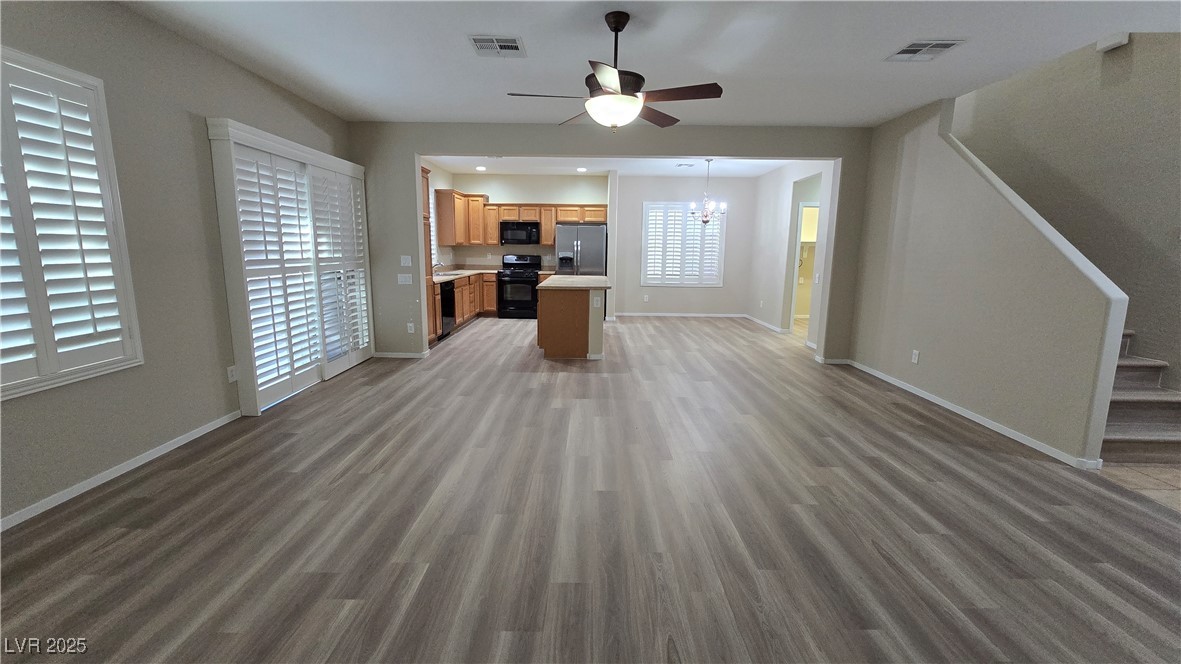 2737 Rimbaud Street Henderson, NV 89044 - Photo 14 of 49 Unfurnished living room with baseboards, visible vents, wood finished floors, and ceiling fan with notable chandelier