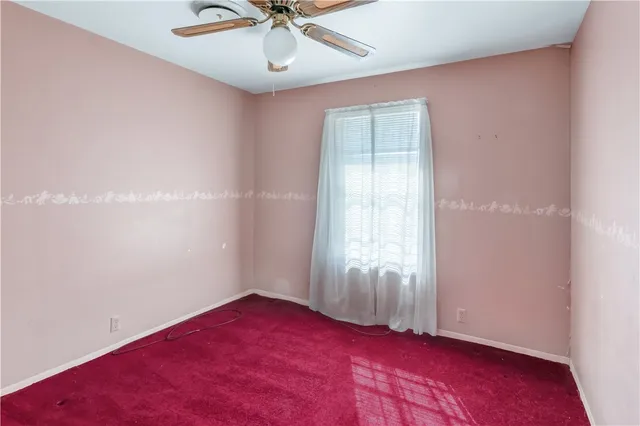 an empty room with a window and ceiling fan