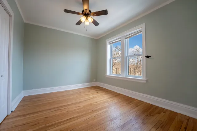 a view of empty room with wooden floor and fan