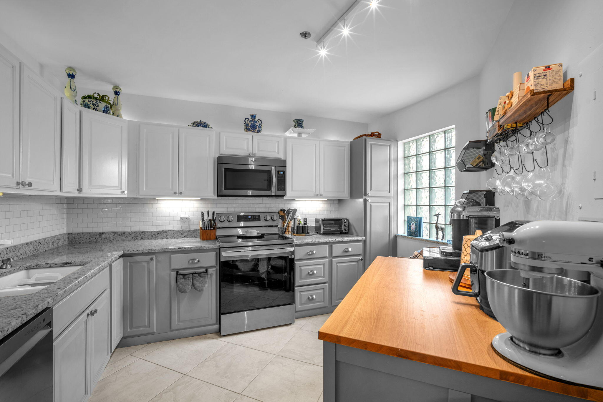 5157 Floria Way, Unit T Boynton Beach, FL 33437 - Photo 2 of 40 a kitchen with stainless steel appliances granite countertop a stove top oven a sink dishwasher a dining table and chairs with wooden floor