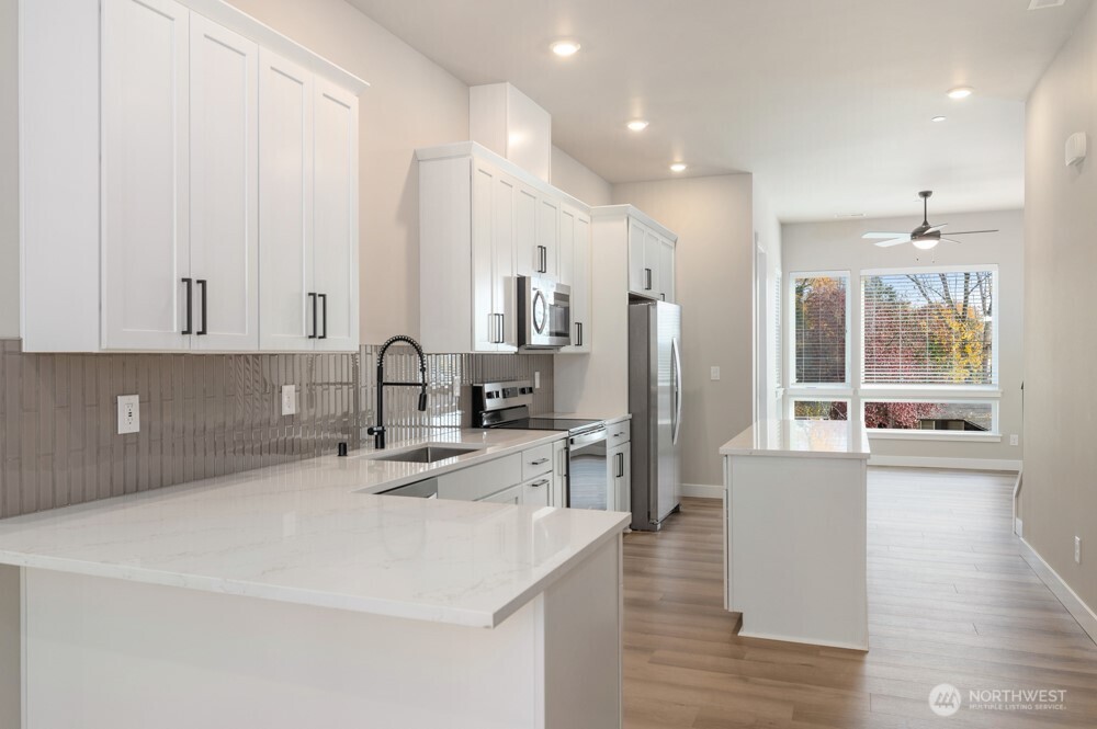 6619 South 128th Street Seattle, WA 98178 - Photo 6 of 20 a kitchen with stainless steel appliances granite countertop a sink a stove and a refrigerator