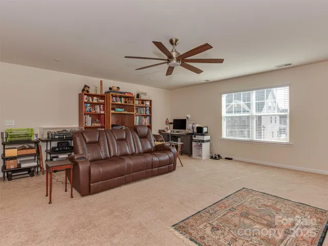 a spacious bedroom with a bed a ceiling fan and a rug