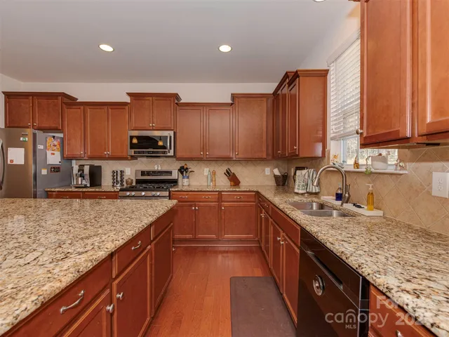 a kitchen with granite countertop stainless steel appliances a sink window and cabinets