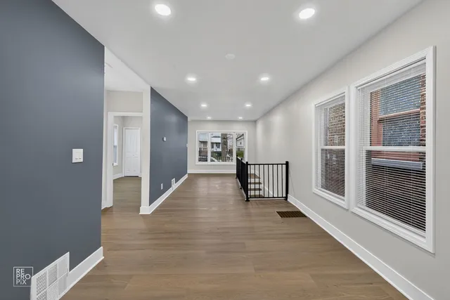 a view of a hallway with wooden floor and windows
