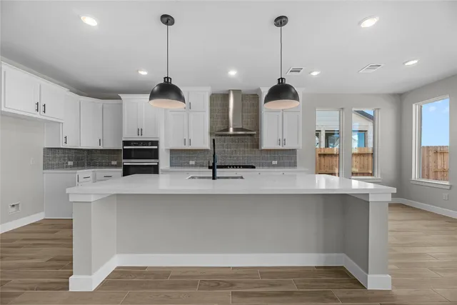 a kitchen with stainless steel appliances granite countertop a sink a stove a refrigerator and white cabinets