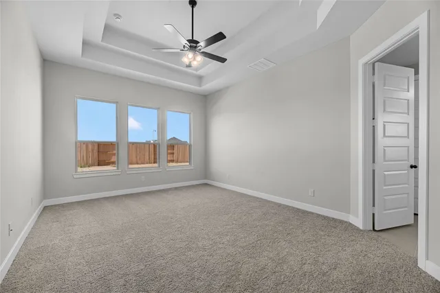 an empty room with chandelier fan and windows