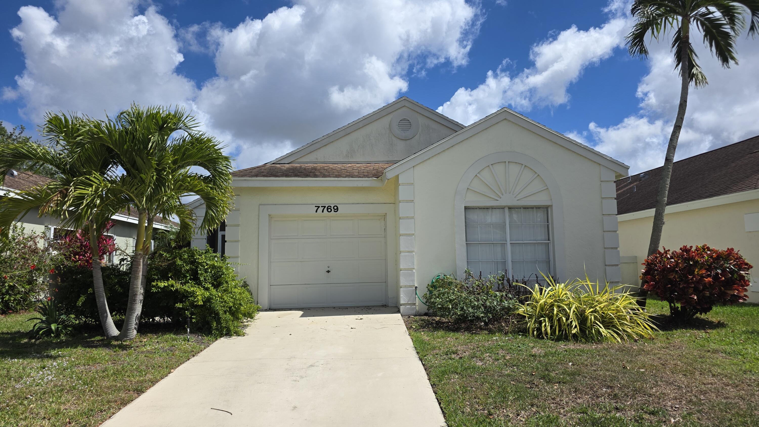 7769 Mansfield Hollow Road Delray Beach, FL 33446 - Photo 1 of 27 a view of a house with a small yard plants and a large tree
