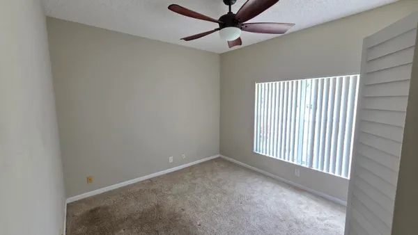 an empty room with a window and a ceiling fan