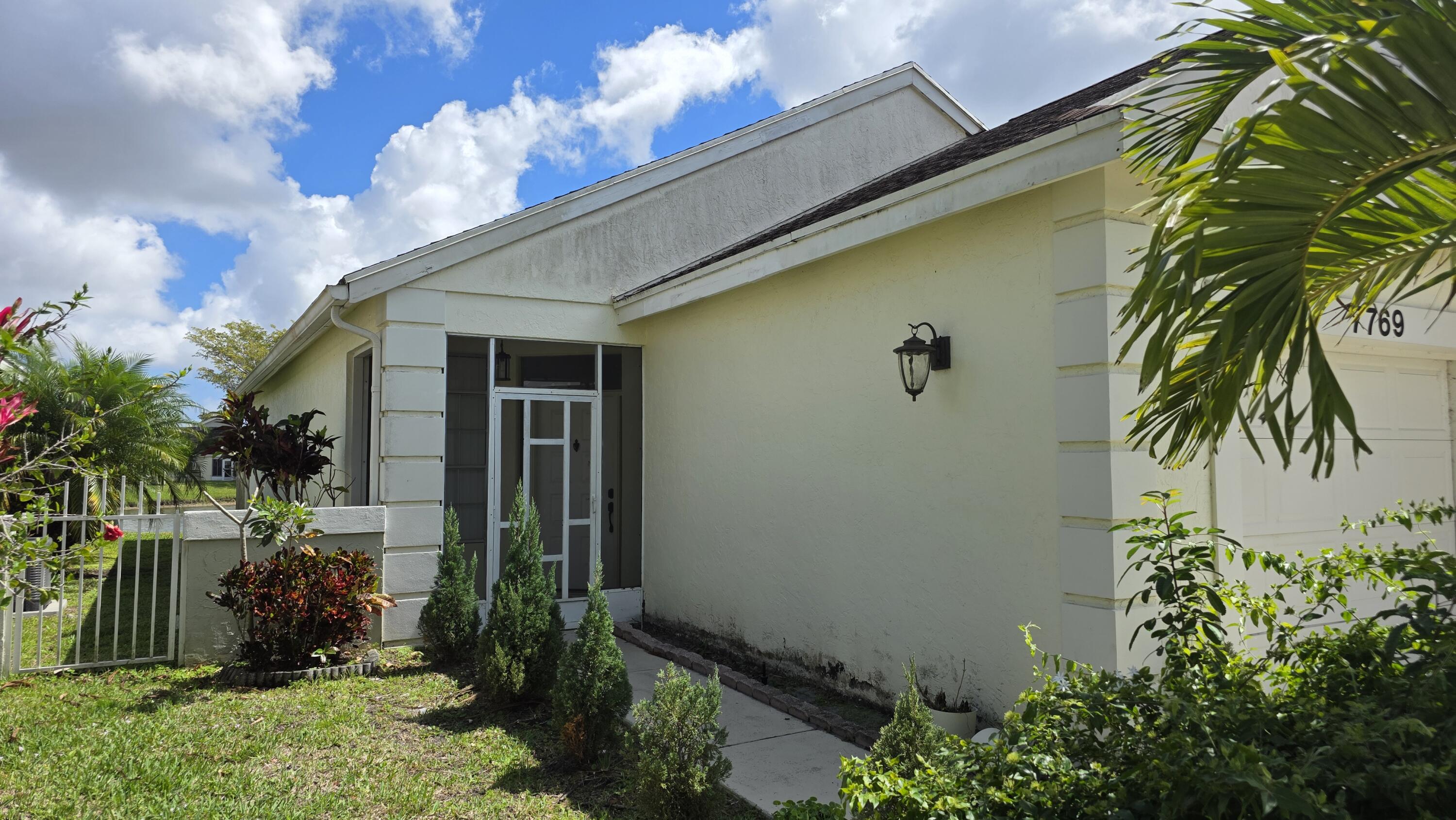 7769 Mansfield Hollow Road Delray Beach, FL 33446 - Photo 4 of 27 a front view of a house with garden