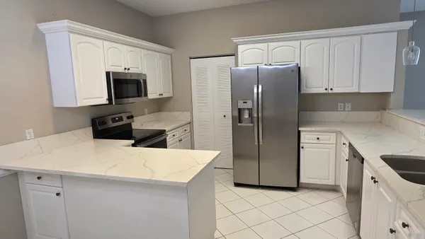 a kitchen with stainless steel appliances a refrigerator sink and white cabinets