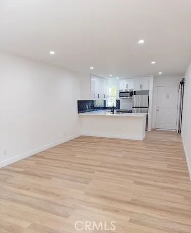 a view of kitchen with kitchen island a sink wooden floor and a refrigerator