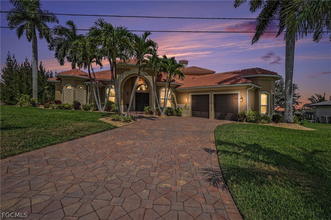 4113 Northwest 26th Street Cape Coral, FL 33993 - Photo 2 of 37 a front view of a house with a garden and a yard
