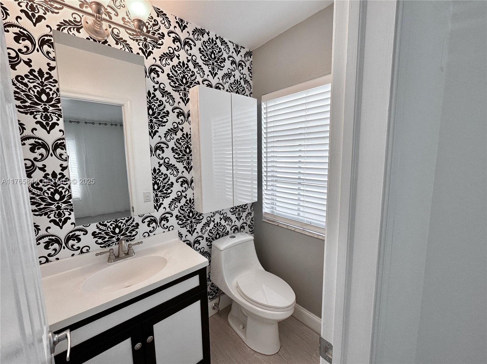 2201 Northeast 66th Street, Unit 1301 Fort Lauderdale, FL 33308 - Photo 12 of 23 a bathroom with a sink a toilet and shower curtain